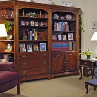 A cozy living room with a large wooden bookshelf filled with books and decorative items.