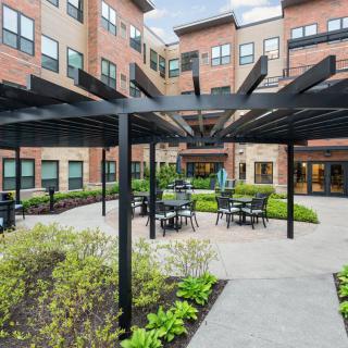 A modern courtyard with a pergola and outdoor seating in an apartment complex.