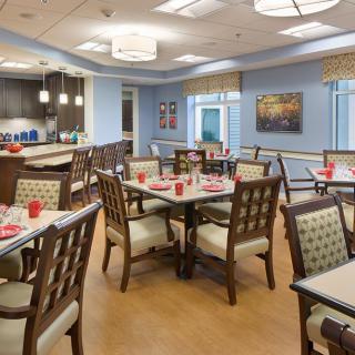 A modern dining area with neatly arranged tables and chairs, featuring warm lighting and tasteful decor.
