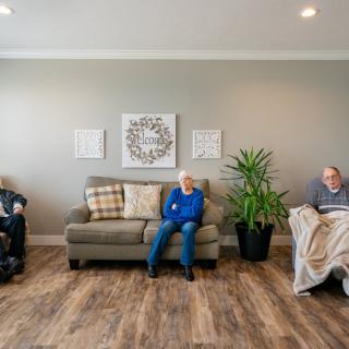 Three seniors seated in a cozy living room, with comfortable seating and a touch of greenery.