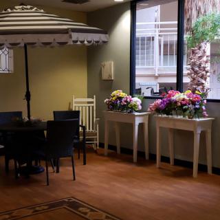 A cozy interior space with tables adorned with vibrant flower arrangements and seating under an indoor umbrella.