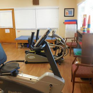 A well-equipped rehabilitation area featuring exercise machines and a comfortable seating arrangement.