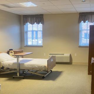 A hospital room with a single bed and two windows, providing a calm and clinical environment.