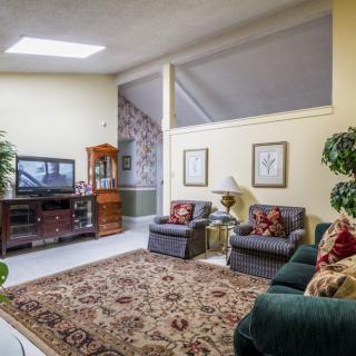 A cozy living room with comfortable seating, a television, and decorative plants.