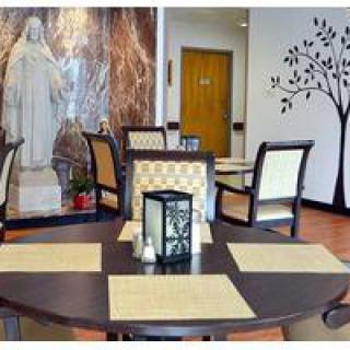An indoor dining area with tables and chairs, featuring a statue and decorative wall art.