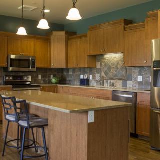 A modern kitchen with wooden cabinets, an island counter, and stainless steel appliances.