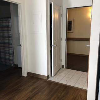 A view of a hallway with doors and different flooring styles.