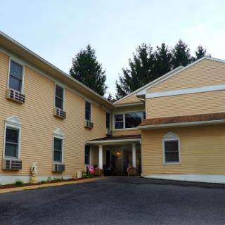 A yellow hotel building featuring an inviting entrance surrounded by greenery.
