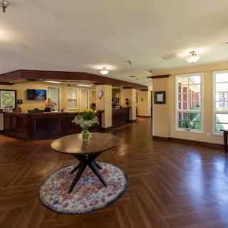A spacious lobby with wooden flooring and a central table adorned with flowers.