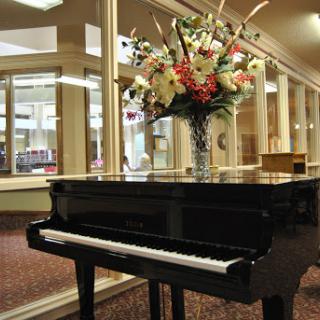 A beautifully arranged floral display next to a grand piano in an elegant interior setting.