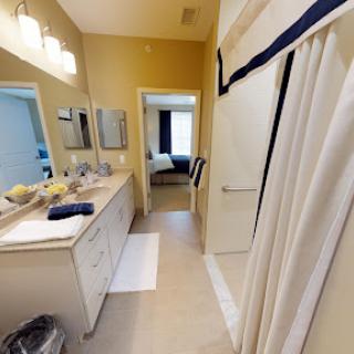 A well-lit bathroom featuring a double vanity, mirrors, and a shower area.