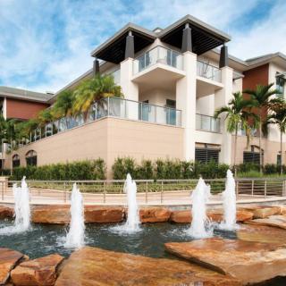 A modern building with fountains and palm trees in the foreground.