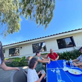 A group of friends enjoying a meal together outdoors on a sunny day.