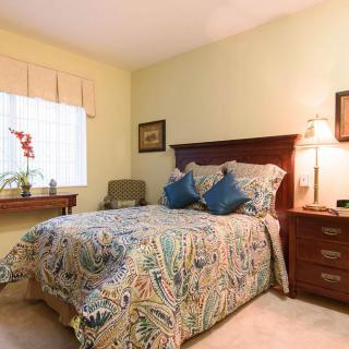 A cozy bedroom with a patterned bedspread, wooden furniture, and warm lighting.