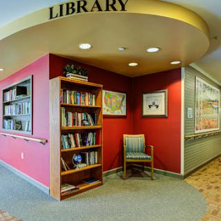 A cozy corner of a library featuring a bookshelf and comfortable seating.