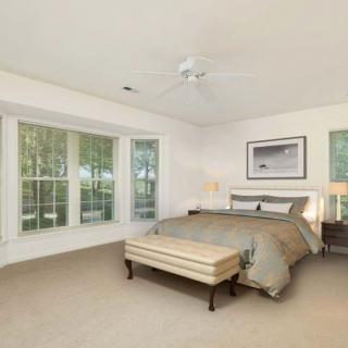 A spacious bedroom with large windows and neutral decor.