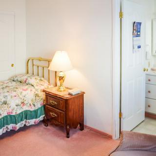 A cozy bedroom with a floral bedspread, nightstand, and lamp.