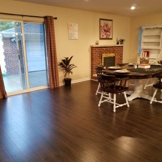 A cozy living room with a hardwood floor, featuring a dining area and fireplace.