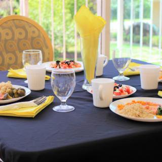 A beautifully arranged dining table with various dishes, complemented by yellow napkins and glassware.