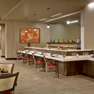 A modern restaurant interior featuring a bar with seating and contemporary artwork.