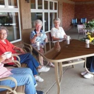 A group of seniors enjoying coffee together outdoors.