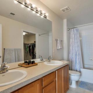 A modern bathroom featuring a double sink vanity and large mirror, with a shower area enclosed by a curtain.