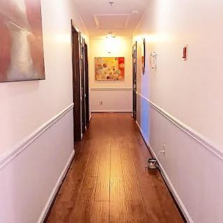 A brightly lit hallway with wooden flooring and artwork on the walls.