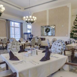 A beautifully decorated dining room with elegant table settings, chandeliers, and a Christmas tree.