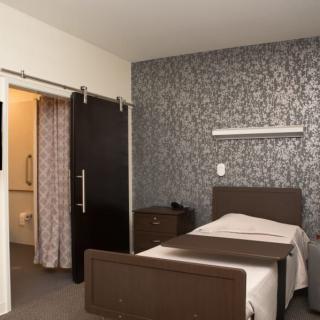 A hospital room with a single bed, modern design, and decorative wallpaper.