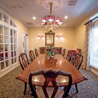 A traditional dining room featuring a large wooden table and chairs, adorned with an elegant chandelier and classic decor.
