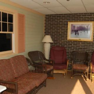 A cozy waiting room with a sofa, chairs, lamp, and a painting on the wall.