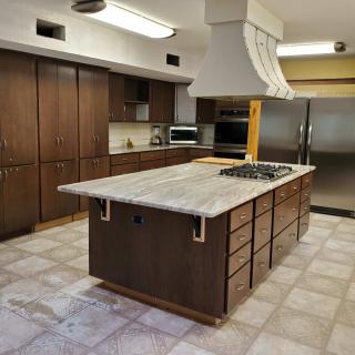 Modern kitchen with a central island featuring wood cabinets and stainless steel appliances.