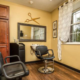 A cozy hair salon room with a barber chair, mirror, and scissors wall decoration.