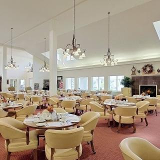 A spacious and elegant dining room with well-arranged tables and chairs, decorated with chandeliers.