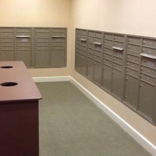 An empty mailroom with rows of metal mailboxes lining the walls.