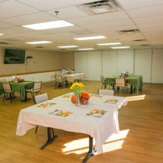 A bright, well-lit dining area with several tables and chairs arranged neatly, adorned with colorful decorations.