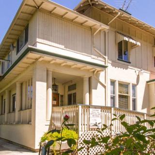 A two-story residential house with a porch and surrounding foliage.