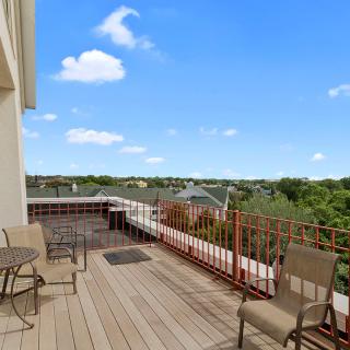 A spacious balcony with outdoor seating and a scenic view of the neighborhood.