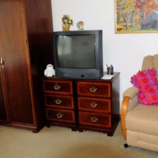 A cozy living room corner featuring a vintage television on a wooden cabinet beside an armchair.