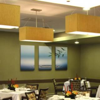 A cozy restaurant interior featuring modern lighting, elegant wall art, and neatly arranged dining tables.