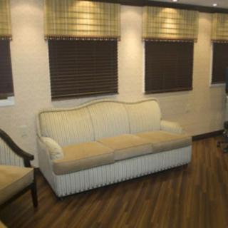 A cozy living room with a cream-colored sofa, wood flooring, and window blinds.