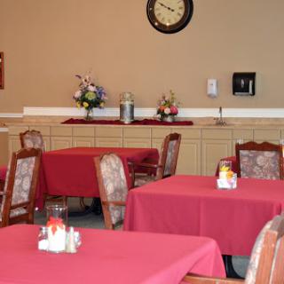 A cozy dining area featuring red tablecloths, wooden furniture, and decorative touches.
