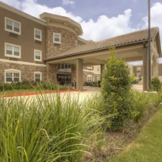 A modern hotel entrance with well-maintained landscaping and a covered driveway.