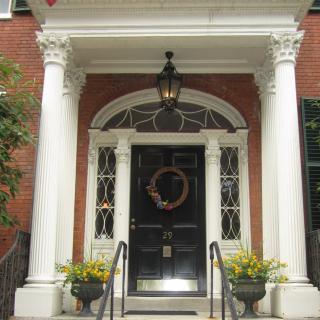 Elegant front entrance with columns and a decorative wreath on the door.