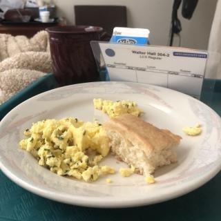 A hospital meal consisting of scrambled eggs and a biscuit on a tray.