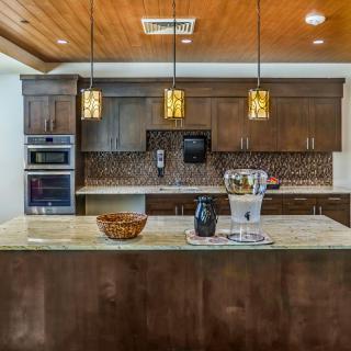 A modern kitchen with a large island, pendant lighting, and sleek wooden cabinets.