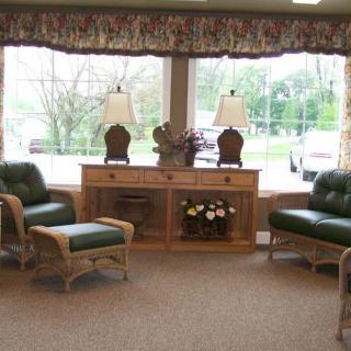 A cozy waiting room with comfortable chairs, decorative lamps, and large windows.