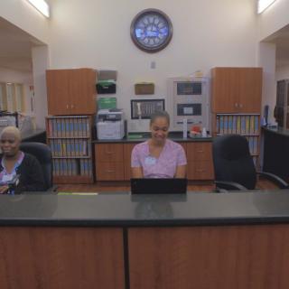 Two people working at the reception desk in an office setting.