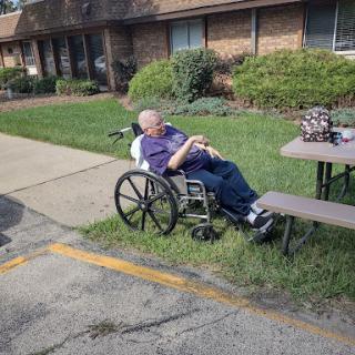 An elderly individual enjoying the outdoors while seated in a wheelchair.