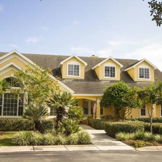 A yellow suburban house with lush landscaping and a sunny day.